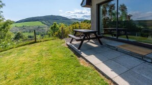 Eine Terrasse mit Tisch und Bänken mit Blick auf ein malerisches Tal.