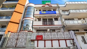 A multi-story building with a prominent 'fab hotels' sign, a 'primero' sign, and a gated entrance with decorative ironwork. - Fabexpress Primero I (Gurugram)