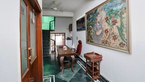 A room with a dining table, chairs, a ceiling fan, a large painting, and a staircase leading to another level. - Fabexpress Primero I (Gurugram)