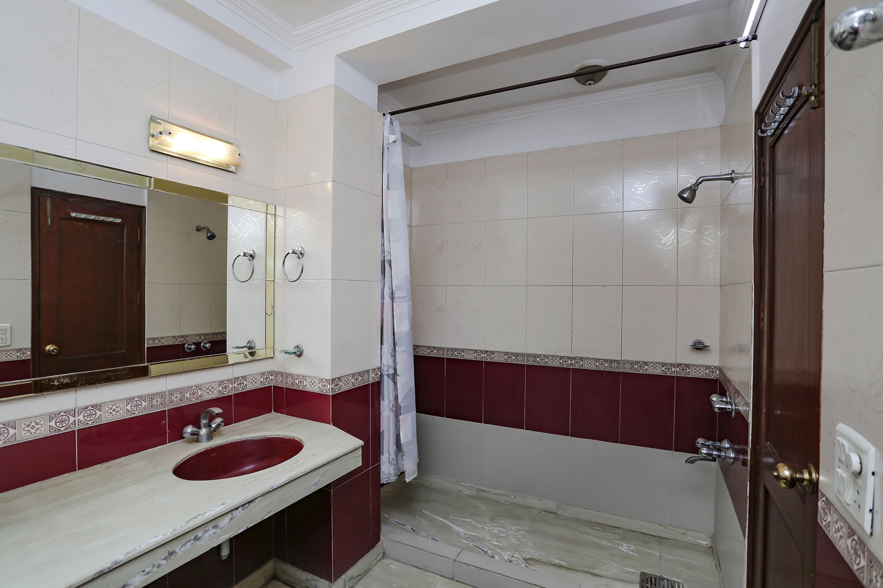 A bathroom with a marble sink, a mirror, a shower, and a door.