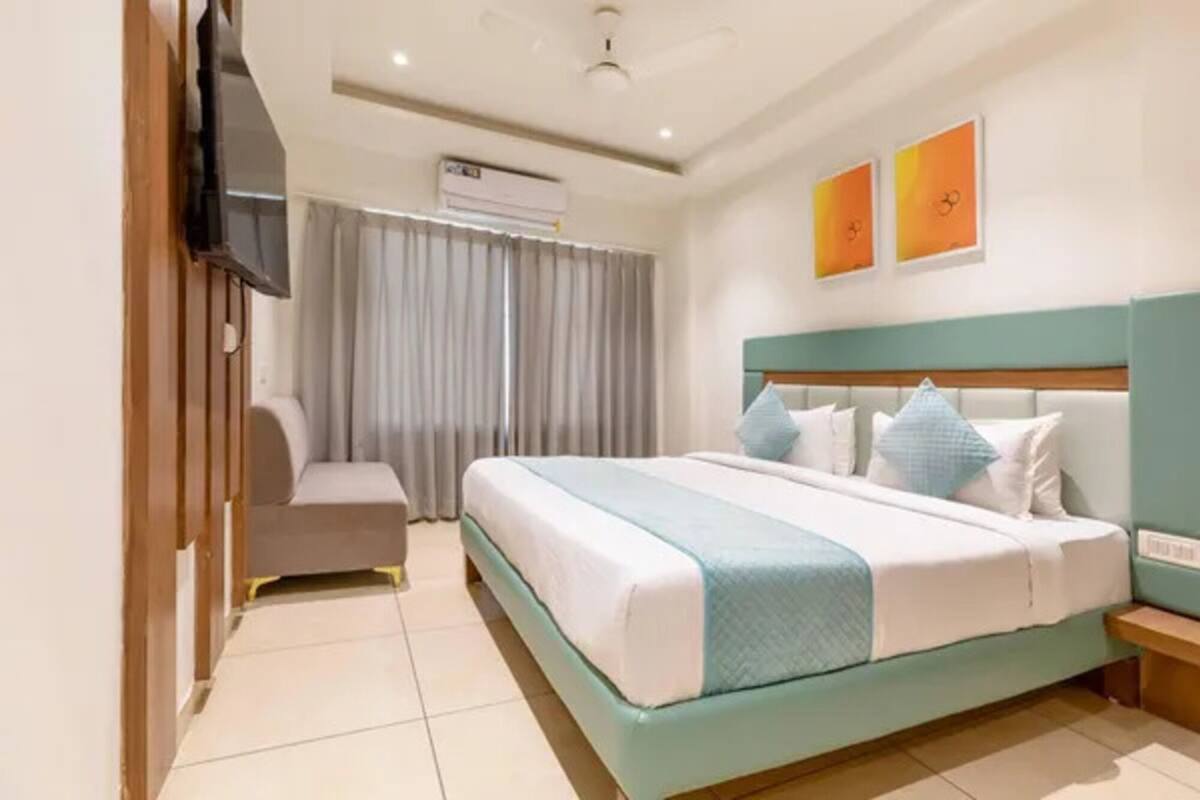 Ein Hotelzimmer mit einem Bett, einem Schreibtisch, einem Sessel, einer Klimaanlage und zwei Wandbildern.