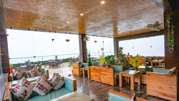 A spacious indoor seating area with wooden furniture and potted plants. - FabHotel Winterline Inn (Dehradun)