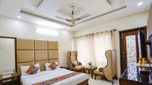 A hotel room with a large bed, a ceiling fan, a TV, a desk, and a chair. - FabHotel Winterline Inn (Dehradun)