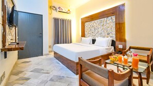 A hotel room with a bed, a dining table with chairs, a small kitchen area, and a bathroom with a shower. - FabHotel Classic Holiday (Jaipur)