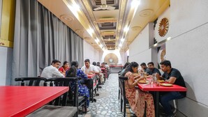 A restaurant with a long counter and multiple tables, featuring a patterned floor and decorative ceiling. - FabHotel Classic Holiday (Jaipur)
