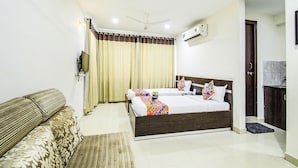 A hotel room with a bed, a sofa, an air conditioning unit, and a television. - Fabhotel Pride Inn (Hyderabad)