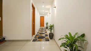 A hallway with a checkered floor, potted plants, and a wooden door at the end. - Fabhotel Pride Inn (Hyderabad)