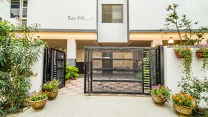 A hotel entrance with a checkered floor, a black gate, and potted plants. - Fabhotel Pride Inn (Hyderabad)