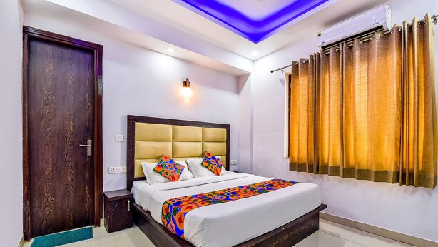 Une chambre à coucher avec un lit en bois, une tête de lit, une table de chevet, une commode, un climatiseur fixé au mur et une fenêtre avec des rideaux.