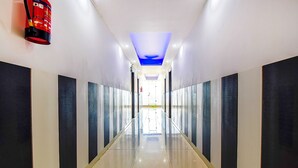 Un long couloir étroit, doté d’un sol réfléchissant et bordé de panneaux sombres et clairs, qui mène à une sortie lumineuse au bout.