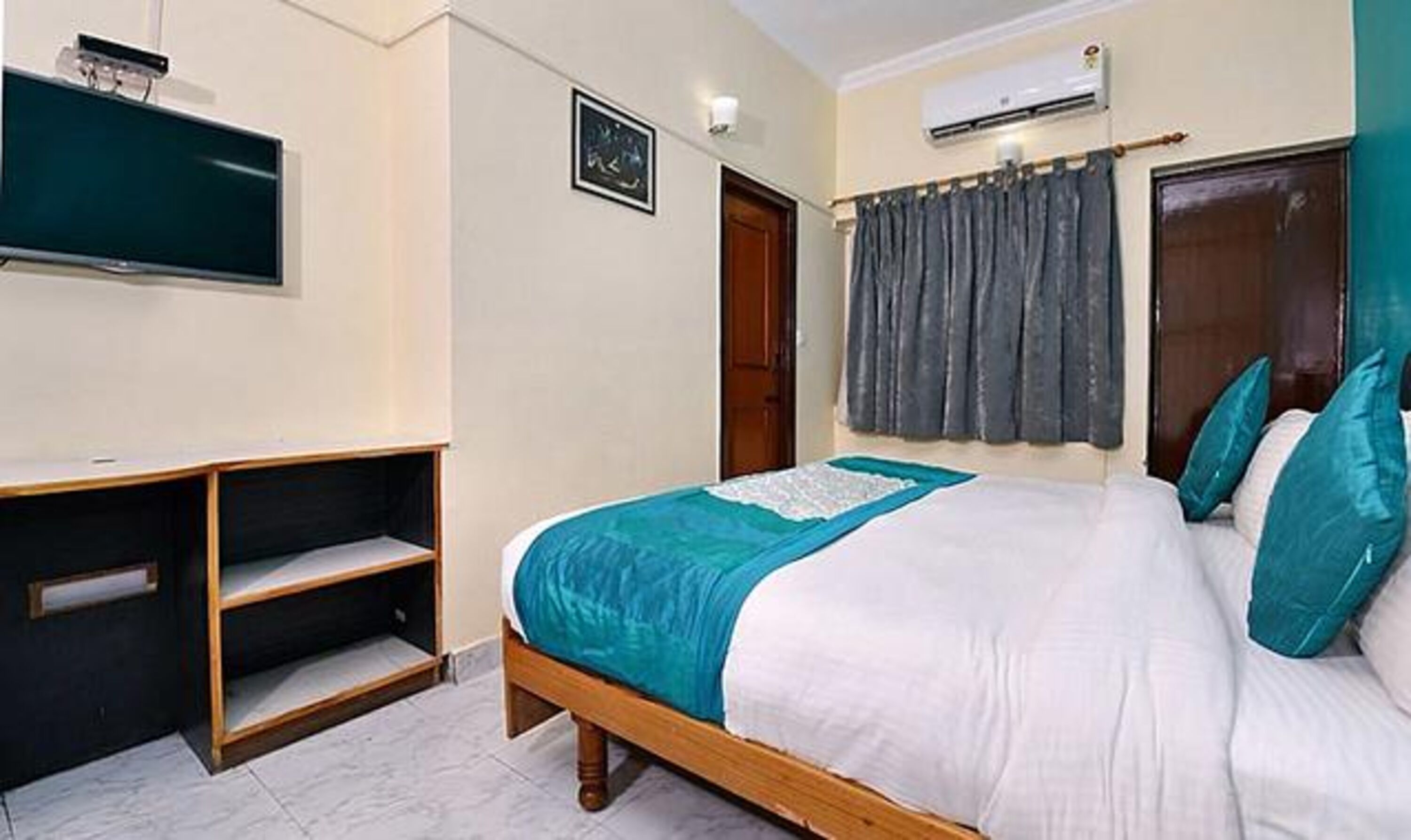 A bedroom with a bed, a TV, a wardrobe, and an air conditioning unit.