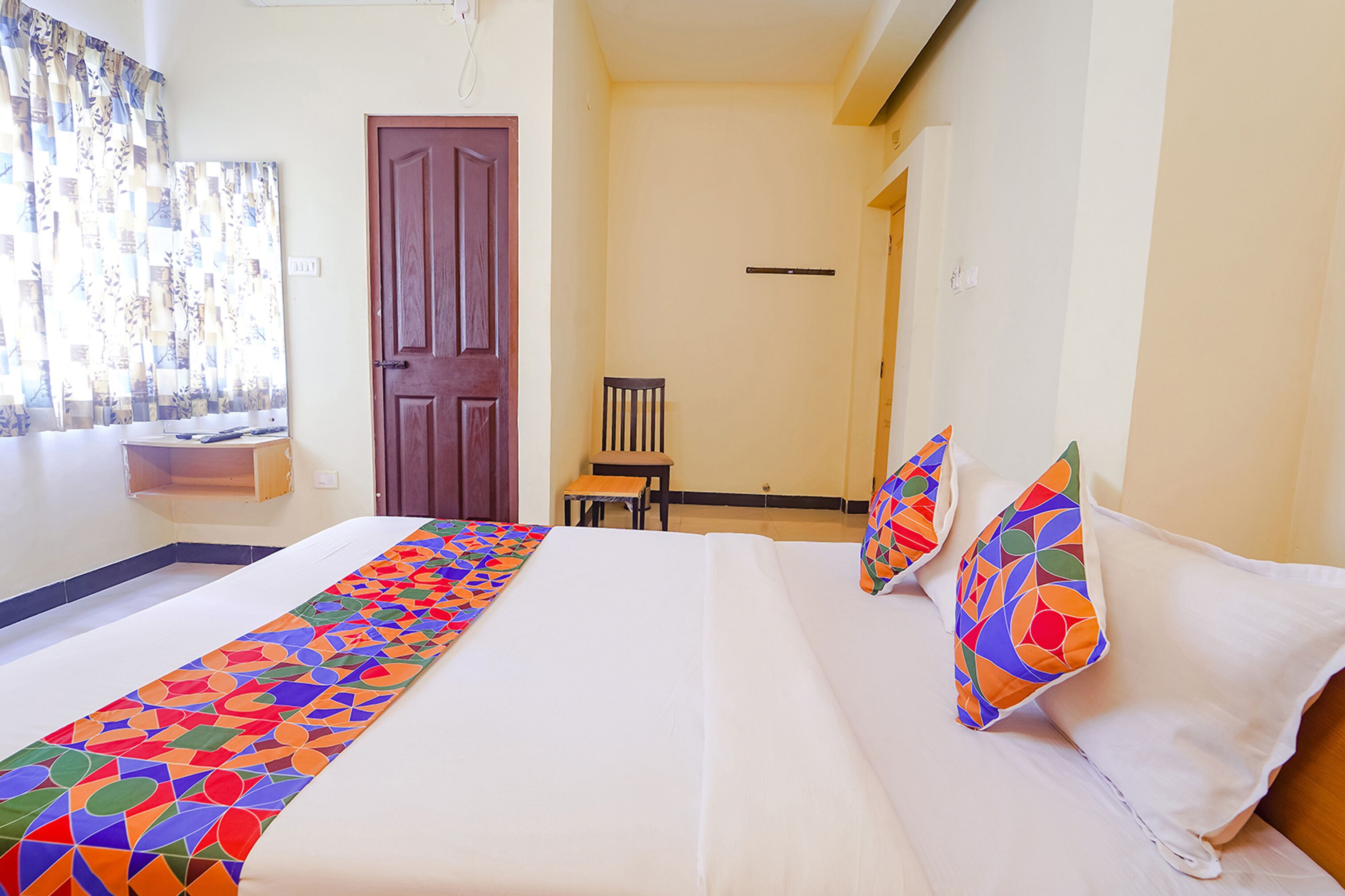 Een hotelkamer met een bed, een stoel, een klein tafeltje en een deur.