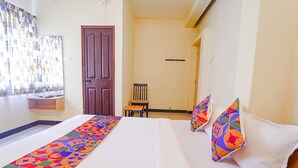 Una habitación de hotel con cama, una silla, una mesita y una puerta.