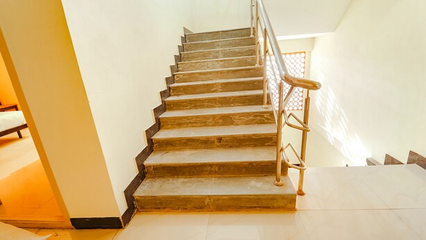 Una escalera de madera con barandillas metálicas que lleva a una habitación con cama y ventana.