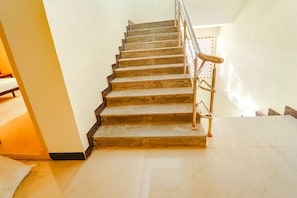 A staircase with wooden steps and metal railings, leading to a room with a bed and a window. - FabHotel Virksham (Coimbatore)