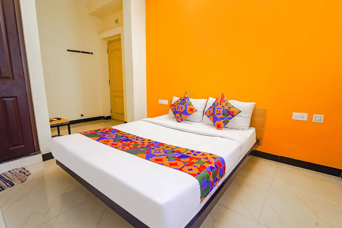A neatly made bed with a colorful blanket, a wooden headboard, and two decorative pillows.