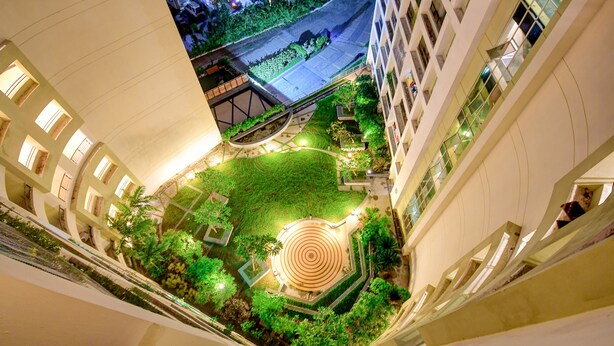 Ein Luftbild eines Hotelinnenhofs mit einem kreisförmigen Garten, umgebenden Gebäuden und einem Weg.