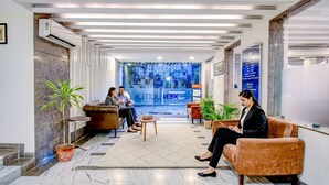 Eine moderne Lobby mit Marmorboden, Ledersitzgelegenheiten und einem großen Fenster mit Blick auf die Stadt.