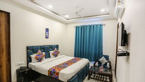A hotel room with a bed, bedside table, TV, and a ceiling fan. - Fabhotel Shiv Rachna (Jaipur)