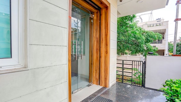 A modern building entrance with a glass door, wooden frame, and a metal gate. - Fabhotel Shiv Rachna (Jaipur)