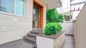 A modern building with a wooden door, a small outdoor area with steps, and a potted plant. - Fabhotel Shiv Rachna (Jaipur)