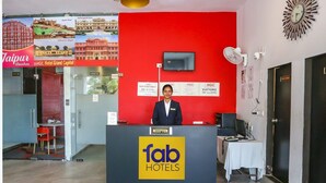 Een receptiebalie met een bordje met daarop 'fab hotels' en een klok aan de muur.
