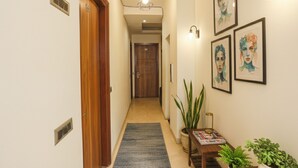 A hallway with wooden doors, a blue carpet, and framed artwork on the walls. - Fabhotel Royal Touch (New Delhi)