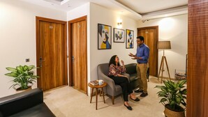 A hotel lobby with wooden doors, a sofa, a coffee table, and two potted plants. - Fabhotel Royal Touch (New Delhi)