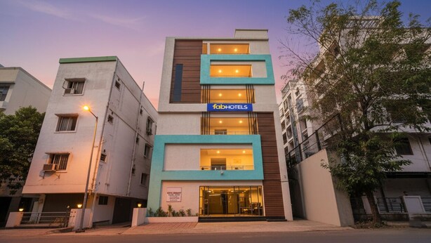 Un bâtiment moderne, orné d’une enseigne « fab hotels », qui se distingue par sa structure à plusieurs étages, ses balcons et son entrée située au niveau du sol.