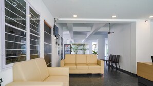Un hall d’entrée moderne avec un canapé beige, un comptoir d’accueil et un espace détente avec des fauteuils.