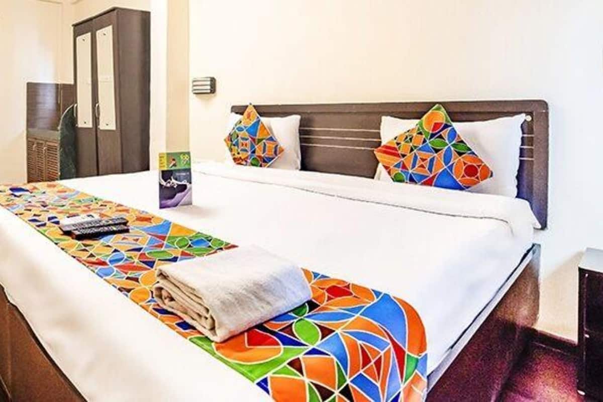 Una habitación de hotel con cama, mesita de noche, espejo y puerta.