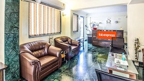 A modern living room with leather sofas, a coffee table, and a kitchen area in the background. - FabHotel East Field Homes (Pune)