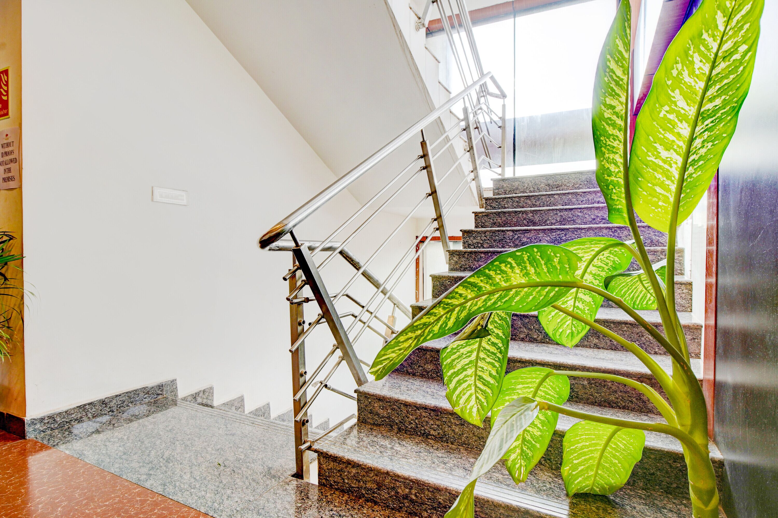 A staircase with metal railings and granite steps, leading to a landing with a glass door.