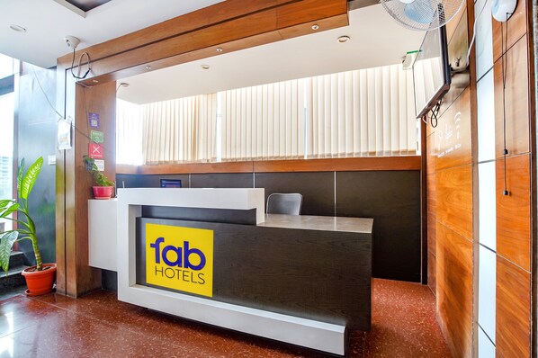 A reception desk with a 'Fab Hotels' sign, a potted plant, and a modern interior design.