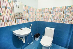 Un baño con pared de azulejos azules, un lavabo blanco y un inodoro.