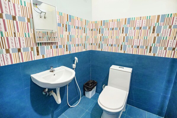 Un baño con pared de azulejos azules, un lavabo blanco y un inodoro.