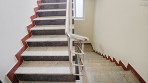 Una escalera con barandilla, peldaños alfombrados y una ventana en la parte superior.
