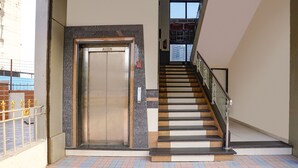 Un escalier avec une rampe en verre menant à un ascenseur.