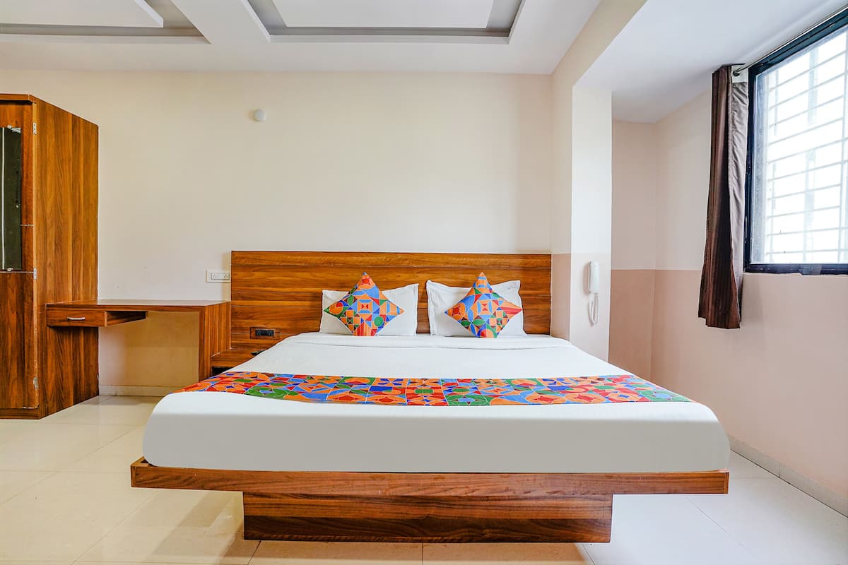 Un dormitorio con estructura de cama de madera, colchón blanco y almohadas coloridas.