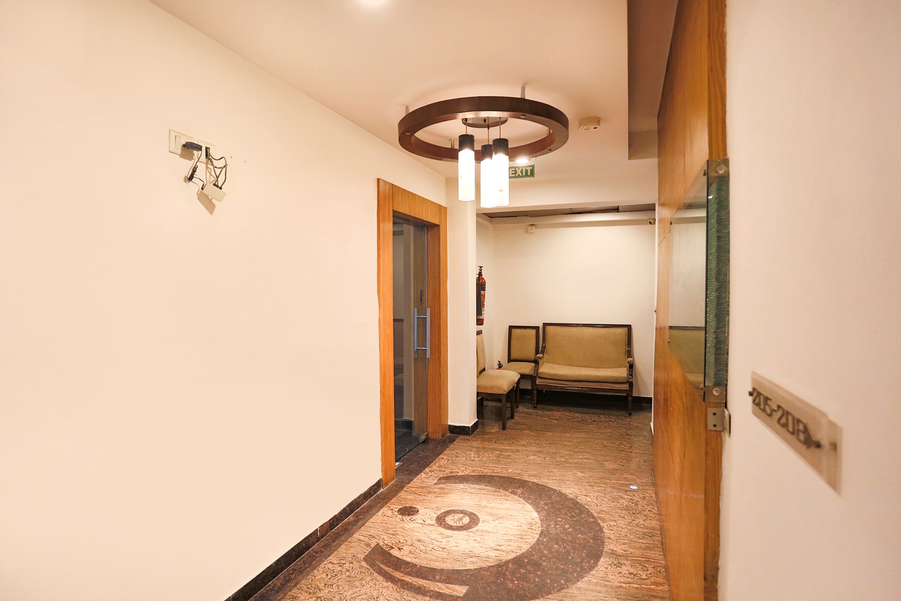 Un pasillo de hotel con piso alfombrado, una puerta de madera y una silla.
