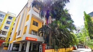 A multi-story building with a prominent 'fabexpress' sign, a gated entrance, and surrounding palm trees. - FabExpress Wakad Stays (Paud)