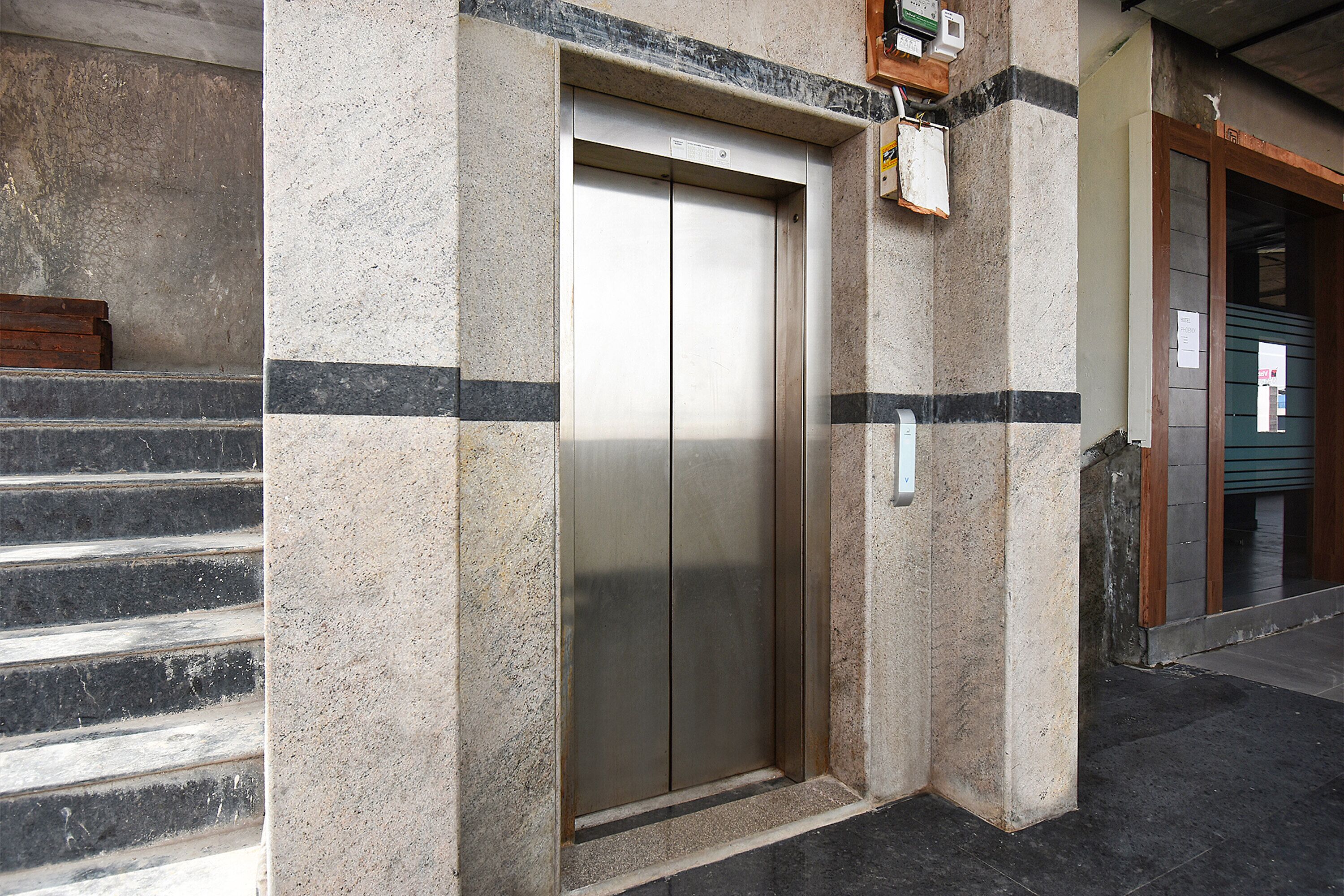 Un ascensor en un edificio de fachada de piedra y puerta metálica.
