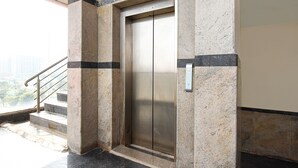 Ein Aufzug in einem Gebäude mit Marmorwand und Metallhandläufen.