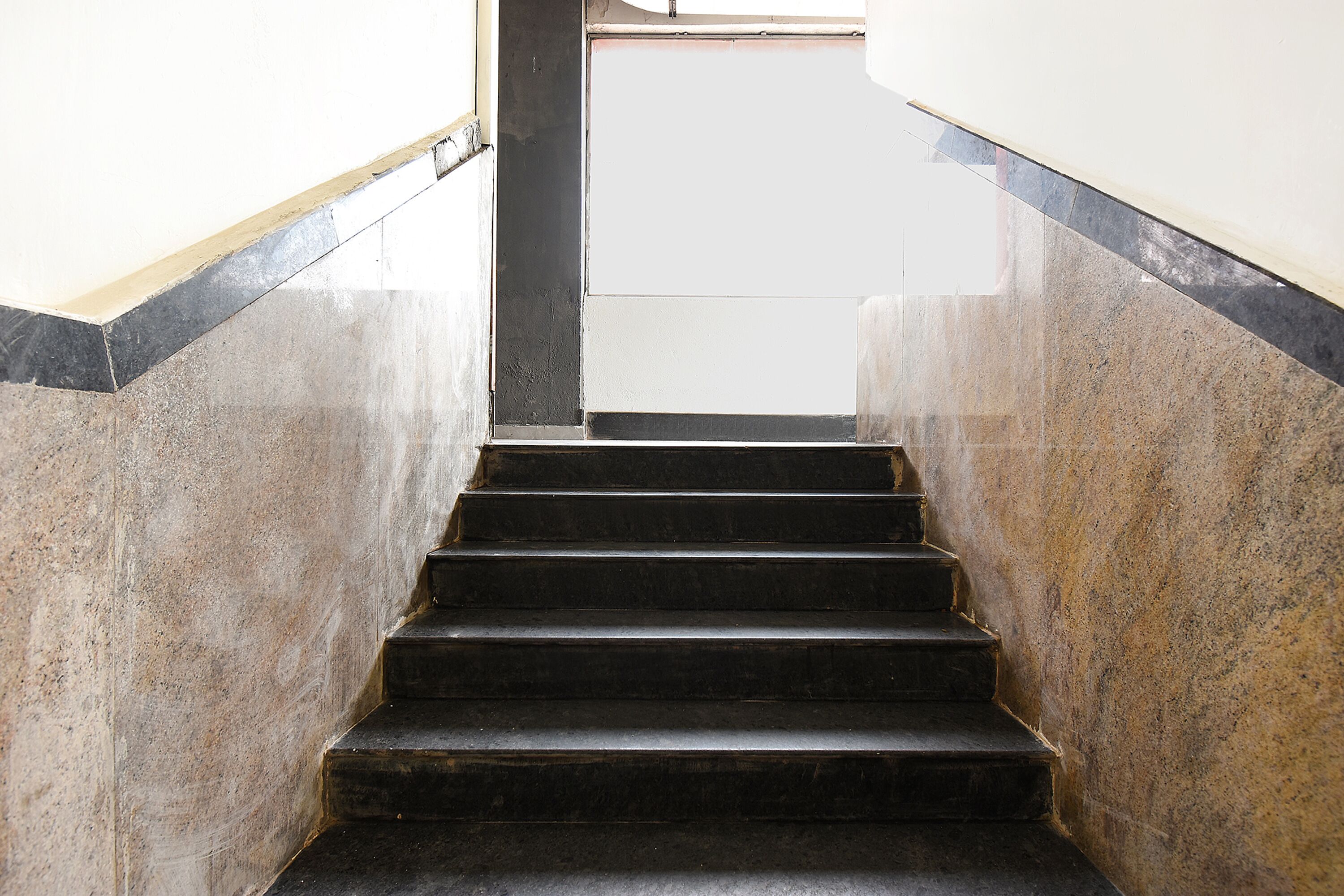 A set of dark stone steps leading upwards, flanked by walls with a contrasting light-colored base.