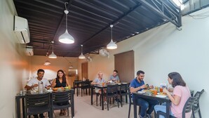 A dining area with multiple tables and chairs, air conditioning units, and hanging pendant lights. - Fabhotel Pride Inn Financia (Hyderabad)