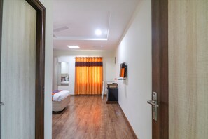 A hotel room with a bed, a desk, a chair, a TV, and a bathroom visible through an open door. - Fabhotel Pride Inn Financia (Hyderabad)