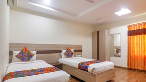 A hotel room with two beds, a wooden headboard, a mirror, and an orange curtain. - Fabhotel Pride Inn Financia (Hyderabad)