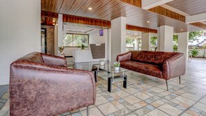 A lobby with leather sofas, a glass coffee table, and a wooden ceiling. - Fabhotel Crystal Homes (Pune)