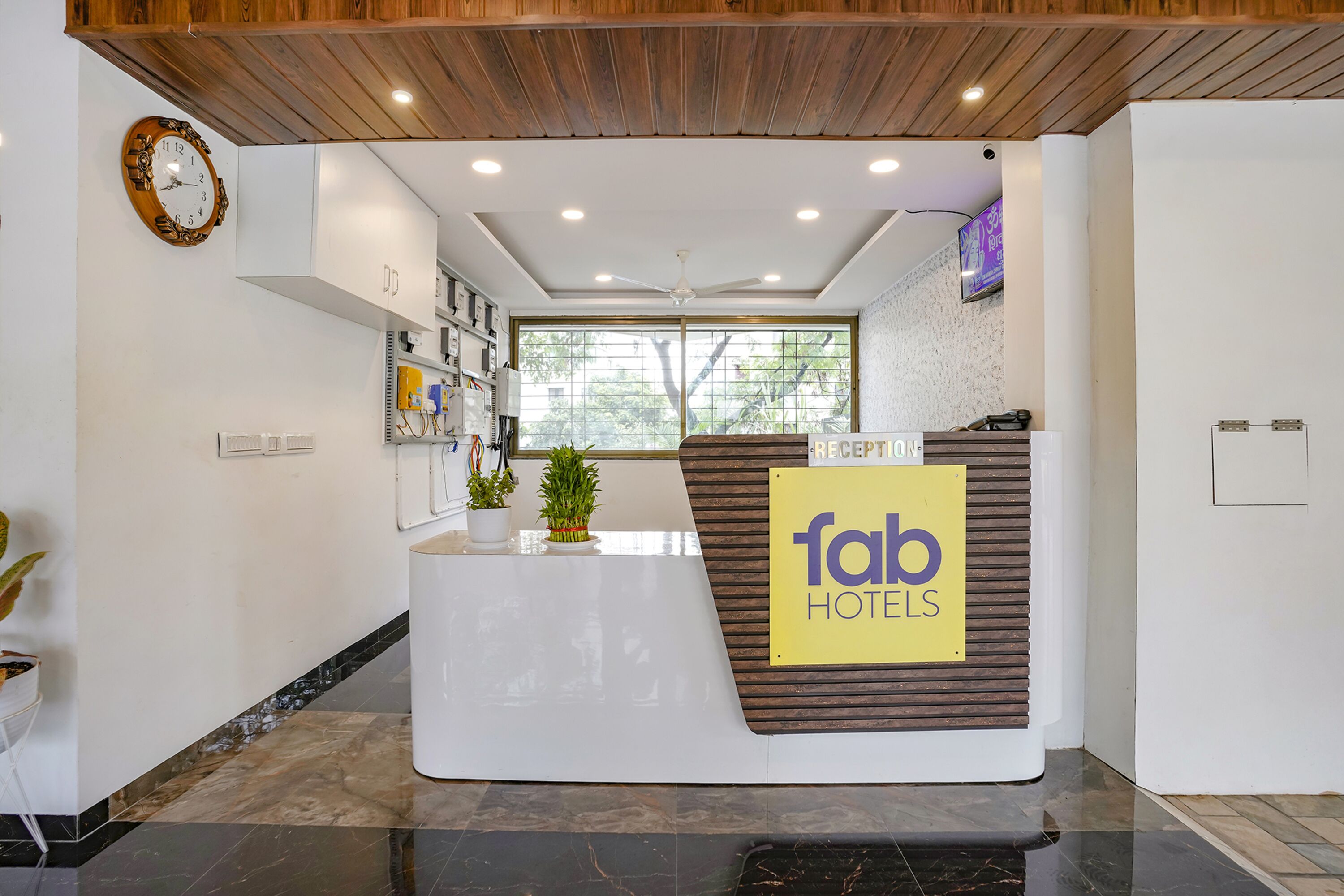 Una recepción con un cartel que dice 'fab hotels' y un reloj en la pared.