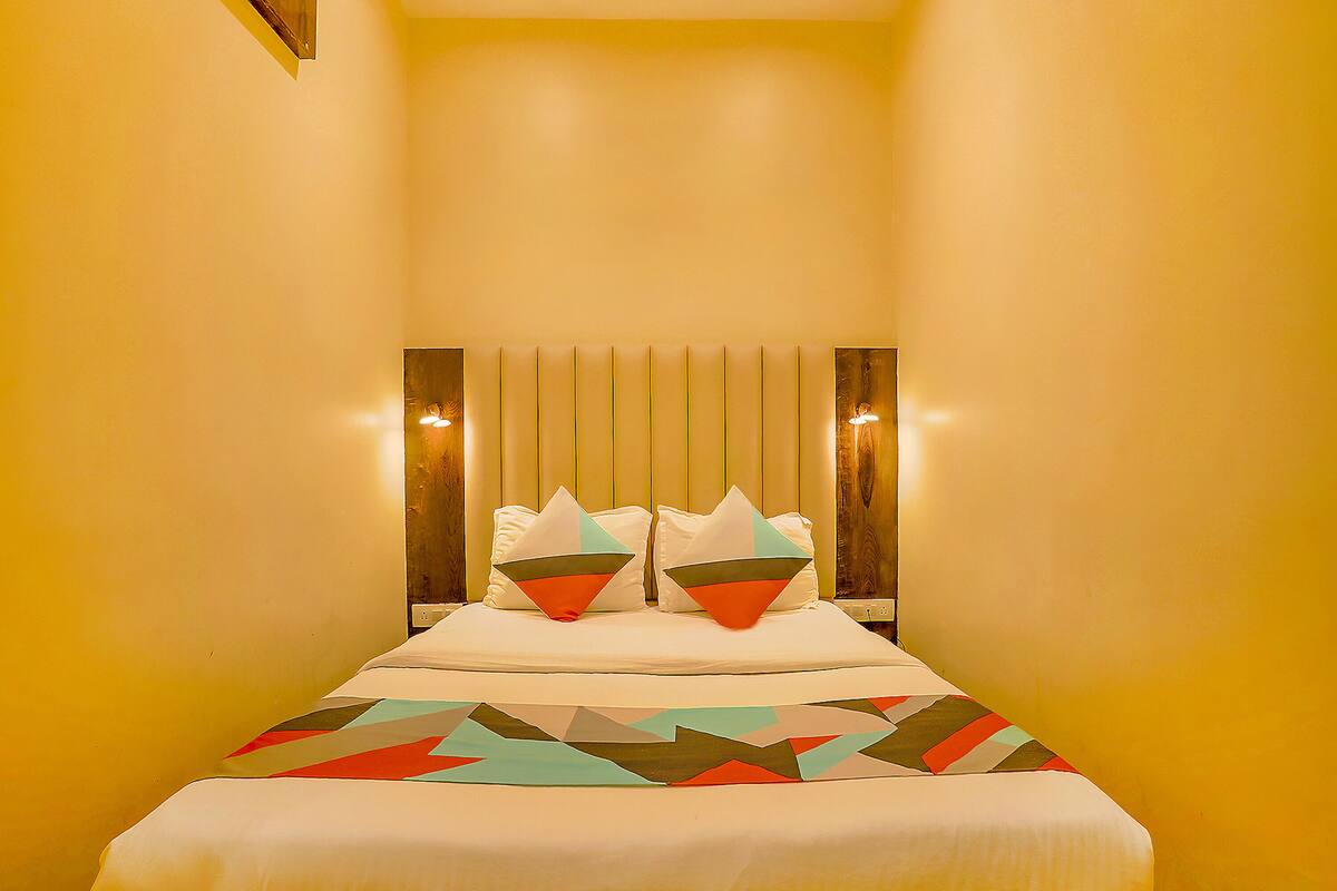 Quarto de hotel com cama, travesseiros e cabeceira.